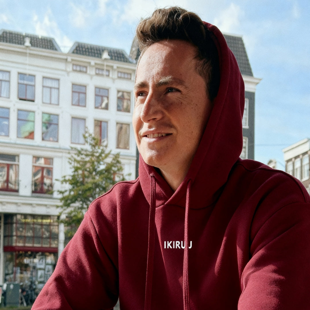 Young man in hoodie enjoys sunlight at outdoor restaurant in Amsterdam