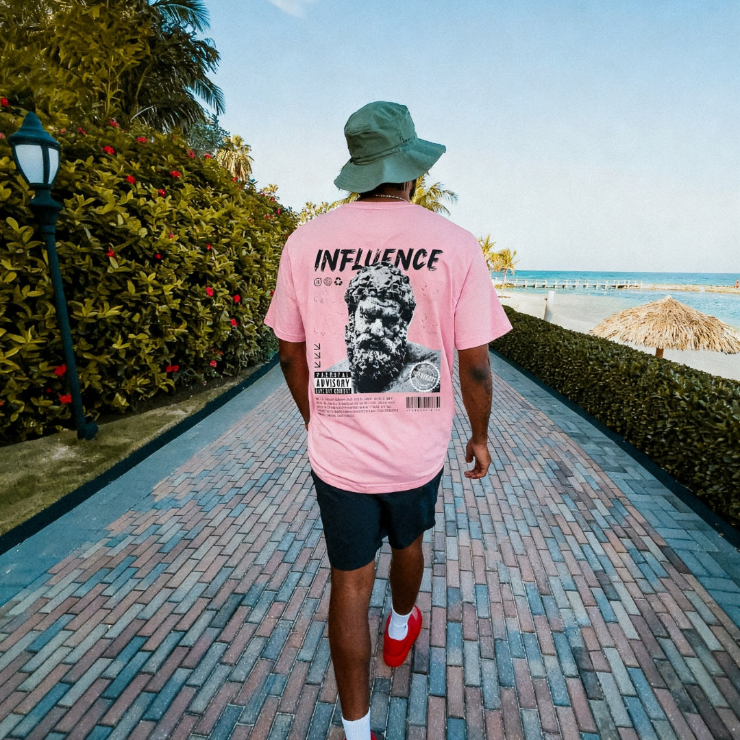 Man wearing a pink t-shirt showcasing the IKIRU branded backdesign walking near the beach