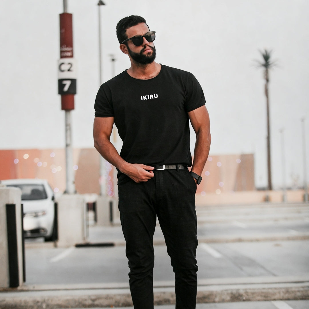 Man wearing a full black outfit with IKIRU branding standing on a parking lot