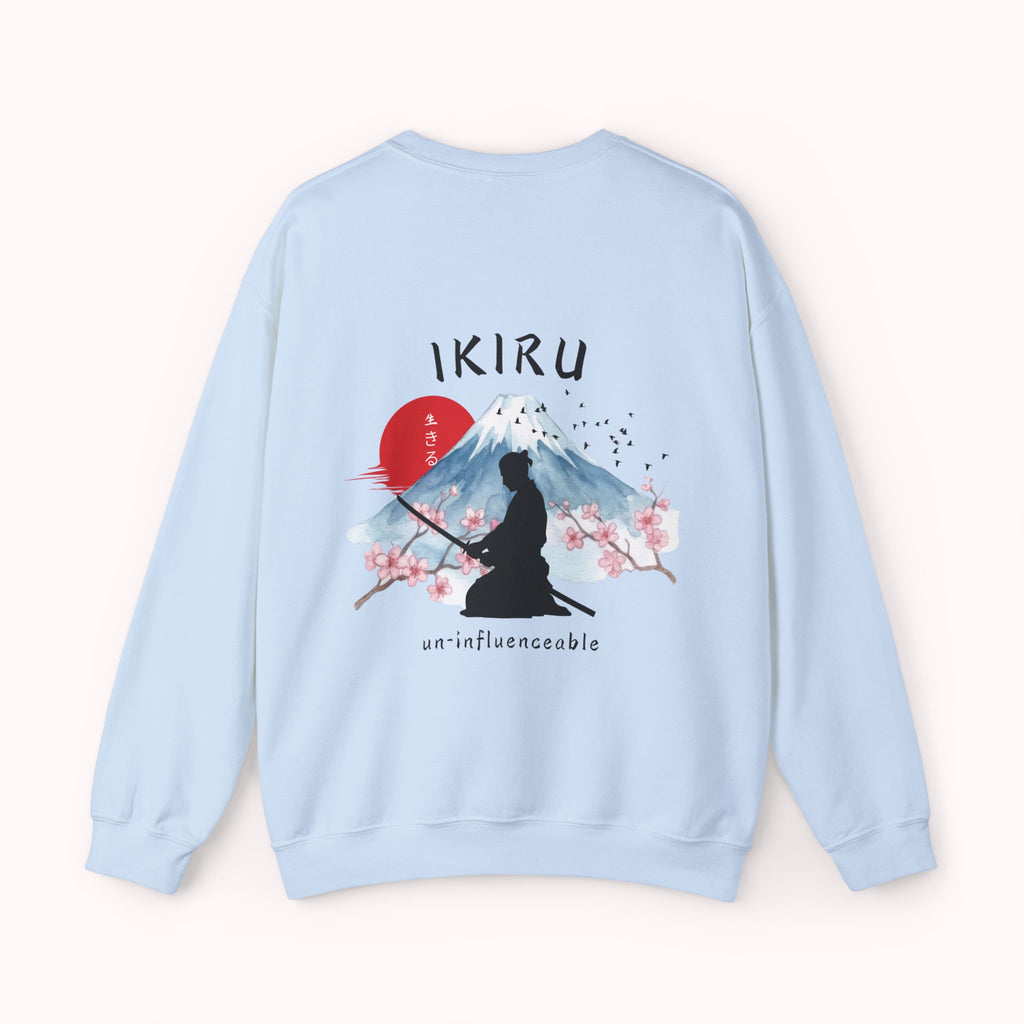 Light blue sweater with a mountain, samurai, and blossom tree design on the back saying 'un-influenceable' against a white background