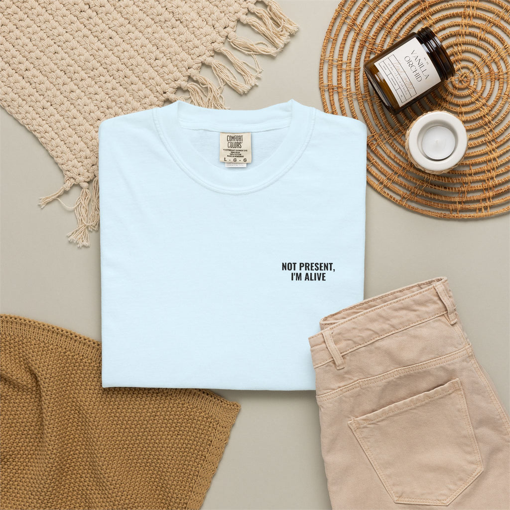 Light blue t-shirt with text, beige pants, and decorative items on a neutral background