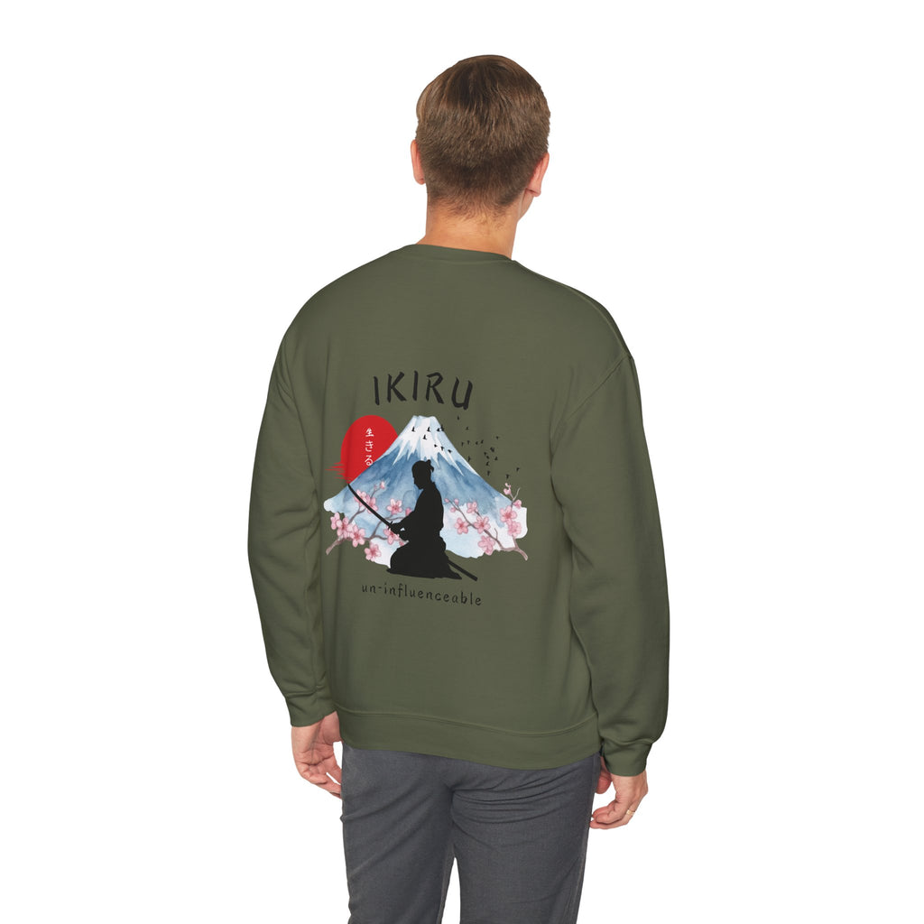 Man wearing green sweater with a mountain, samurai, and blossom tree design on the back saying 'un-influenceable' against a white background