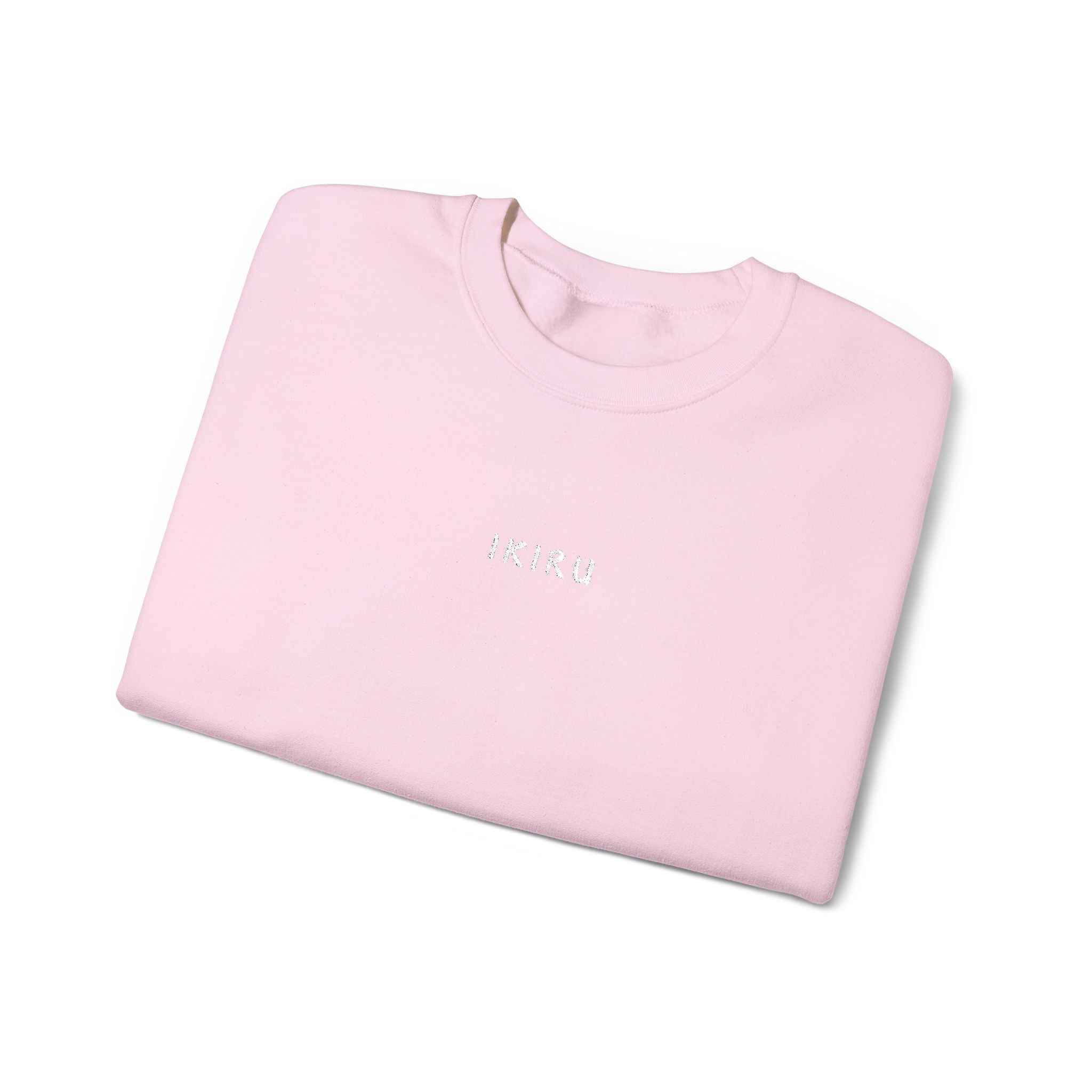 Folded pink sweater with IKIRU logo on a white background