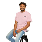 Man wearing a light purple t-shirt with a logo, sitting on a black stool against a white background
