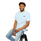 Man sitting on a stool wearing a light blue t-shirt with colorful text.