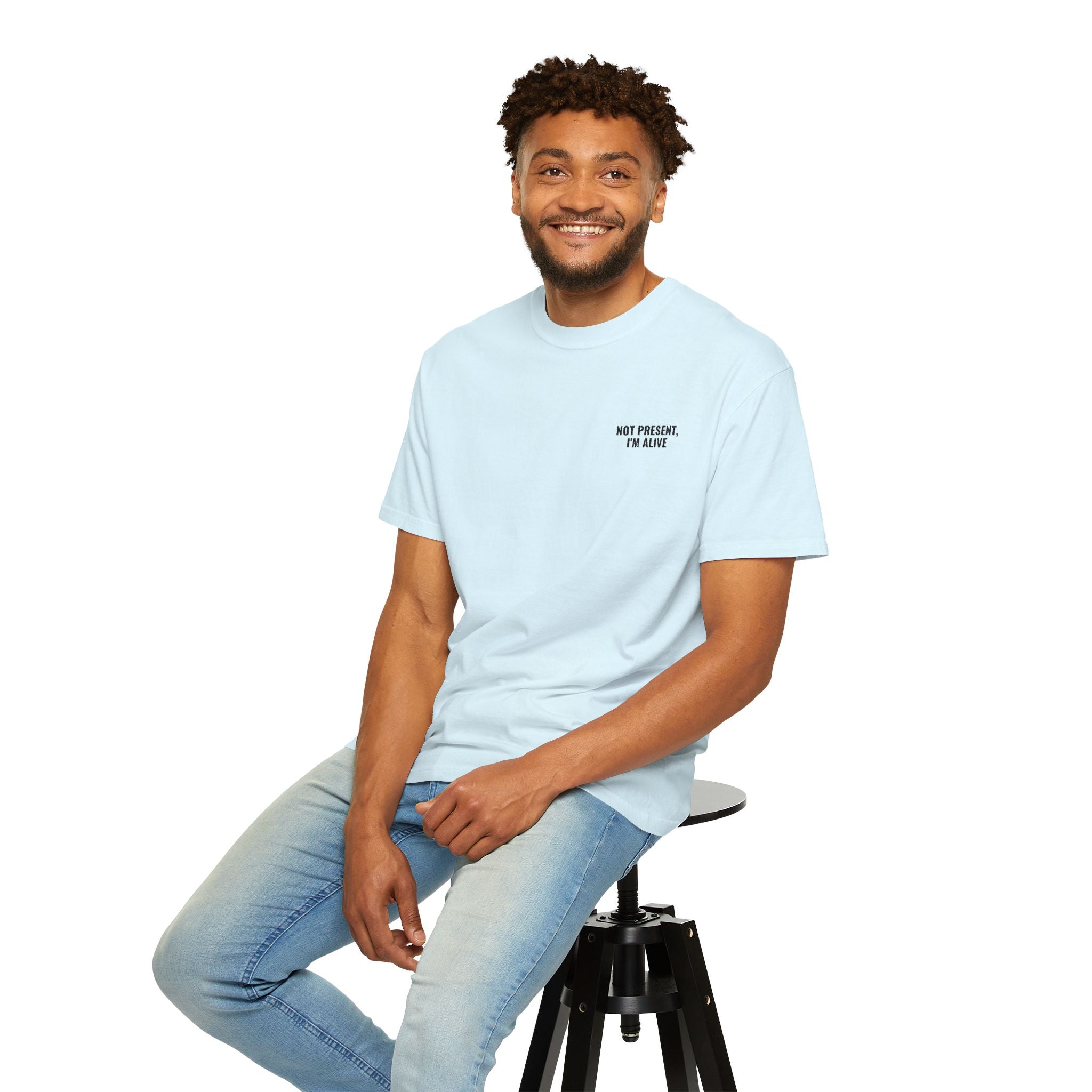 Man sitting on a stool wearing a light blue t-shirt with colorful text.