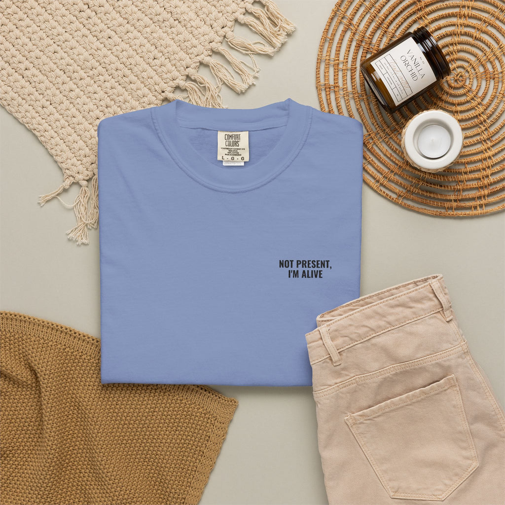 Folded blue t-shirt with text on a neutral surface with accessories.