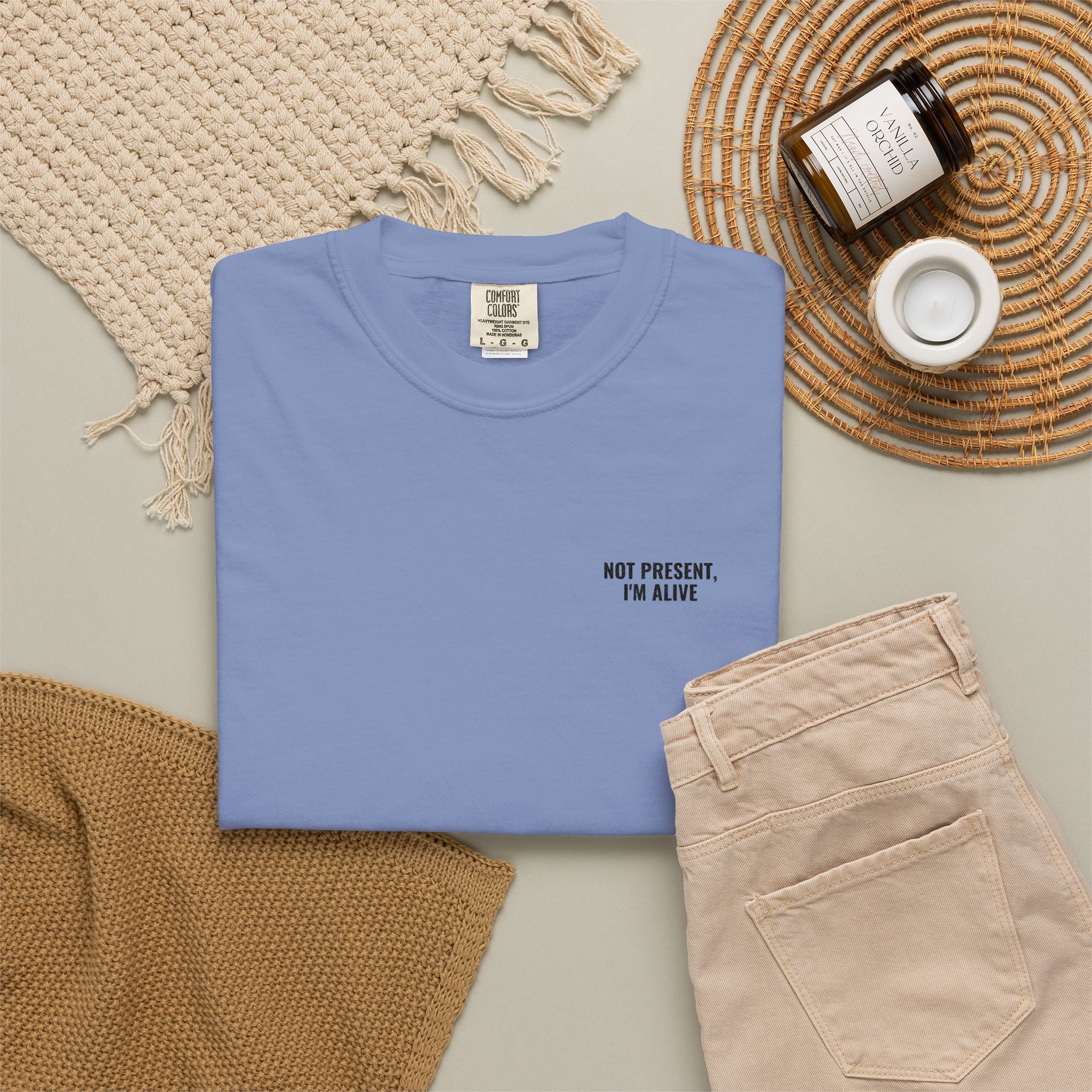 Folded blue t-shirt with text on a neutral surface with accessories.