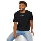 Man wearing a black t-shirt with text design, sitting on a white stool against a white background