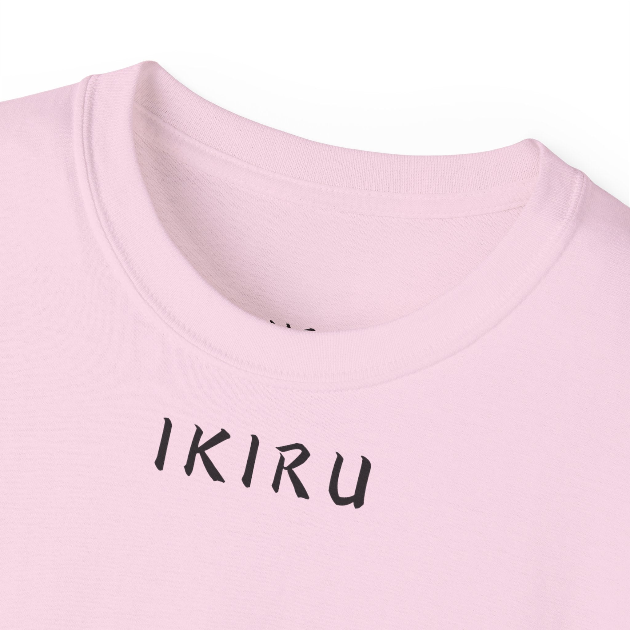 Close-up of a pink shirt with 'IKIRU' printed on it against a white background