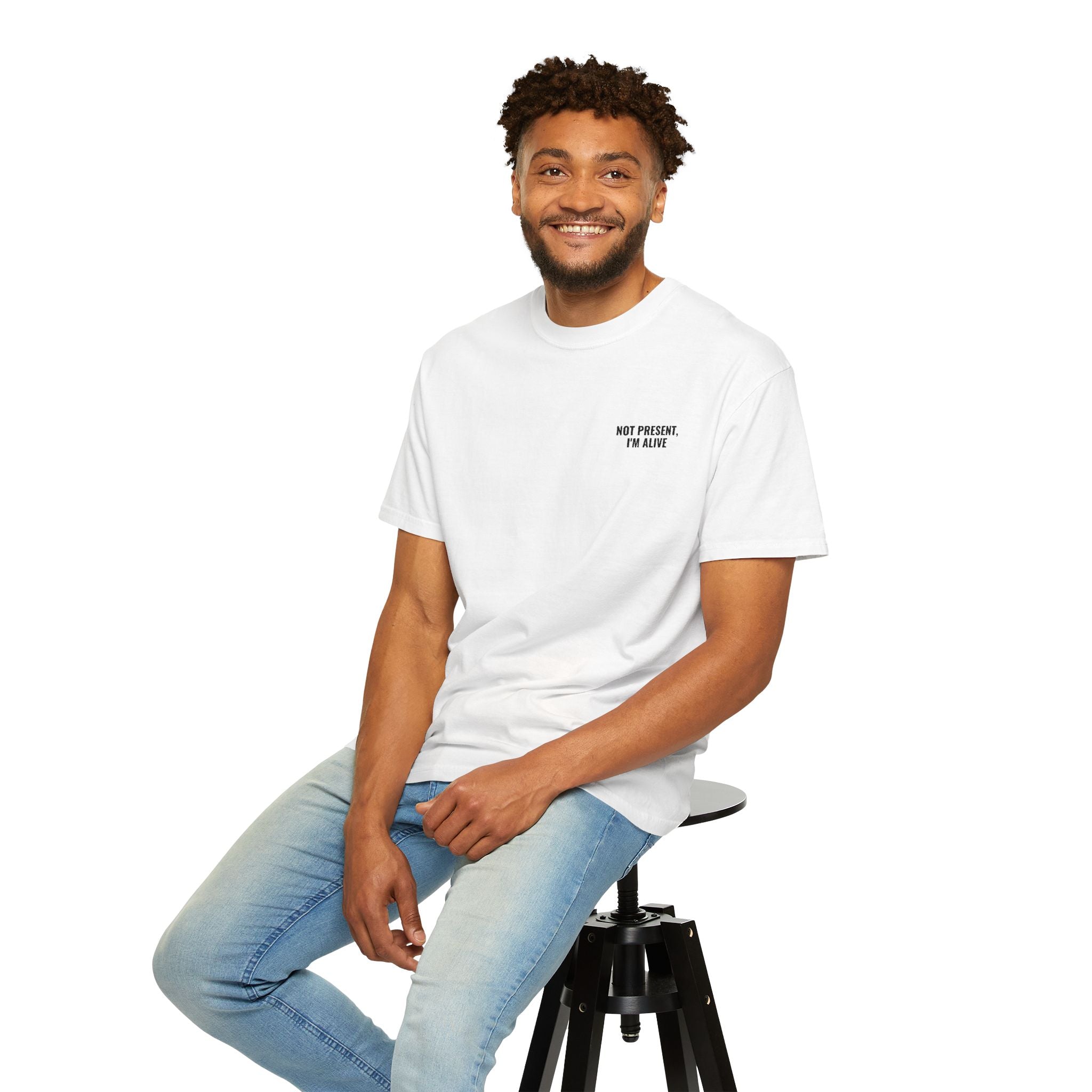 Man sitting on a stool wearing a white t-shirt with a small logo and light blue jeans.