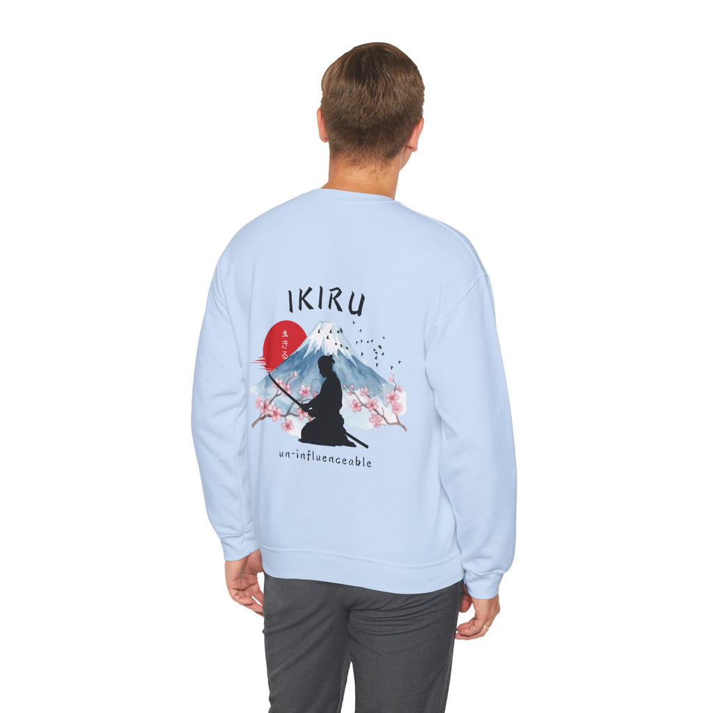 Man wearing light blue sweater with a mountain, samurai, and blossom tree design on the back saying 'un-influenceable' against a white background