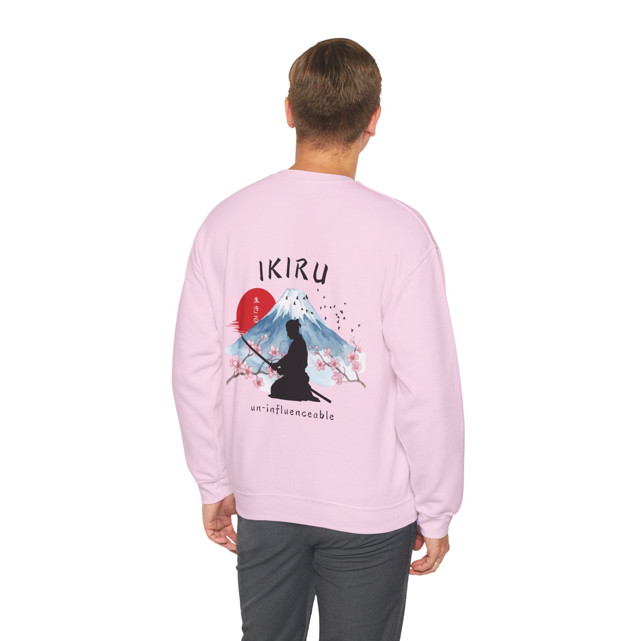 Man wearing pink sweater with a mountain, samurai, and blossom tree design on the back saying 'un-influenceable' against a white background