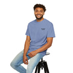 Man sitting on a stool wearing a blue t-shirt with a red heart design.
