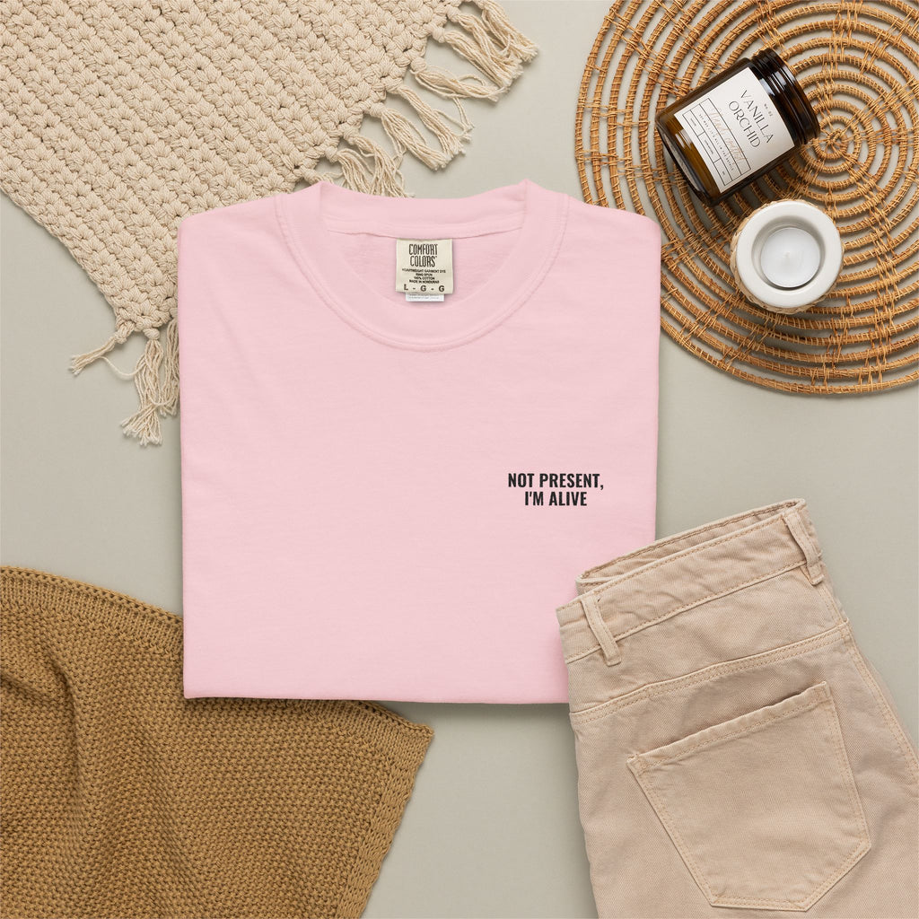 Pink t-shirt with text, beige pants, and decorative items on a neutral background