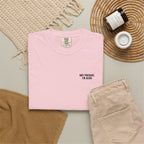 Pink t-shirt with text, beige pants, and decorative items on a neutral background
