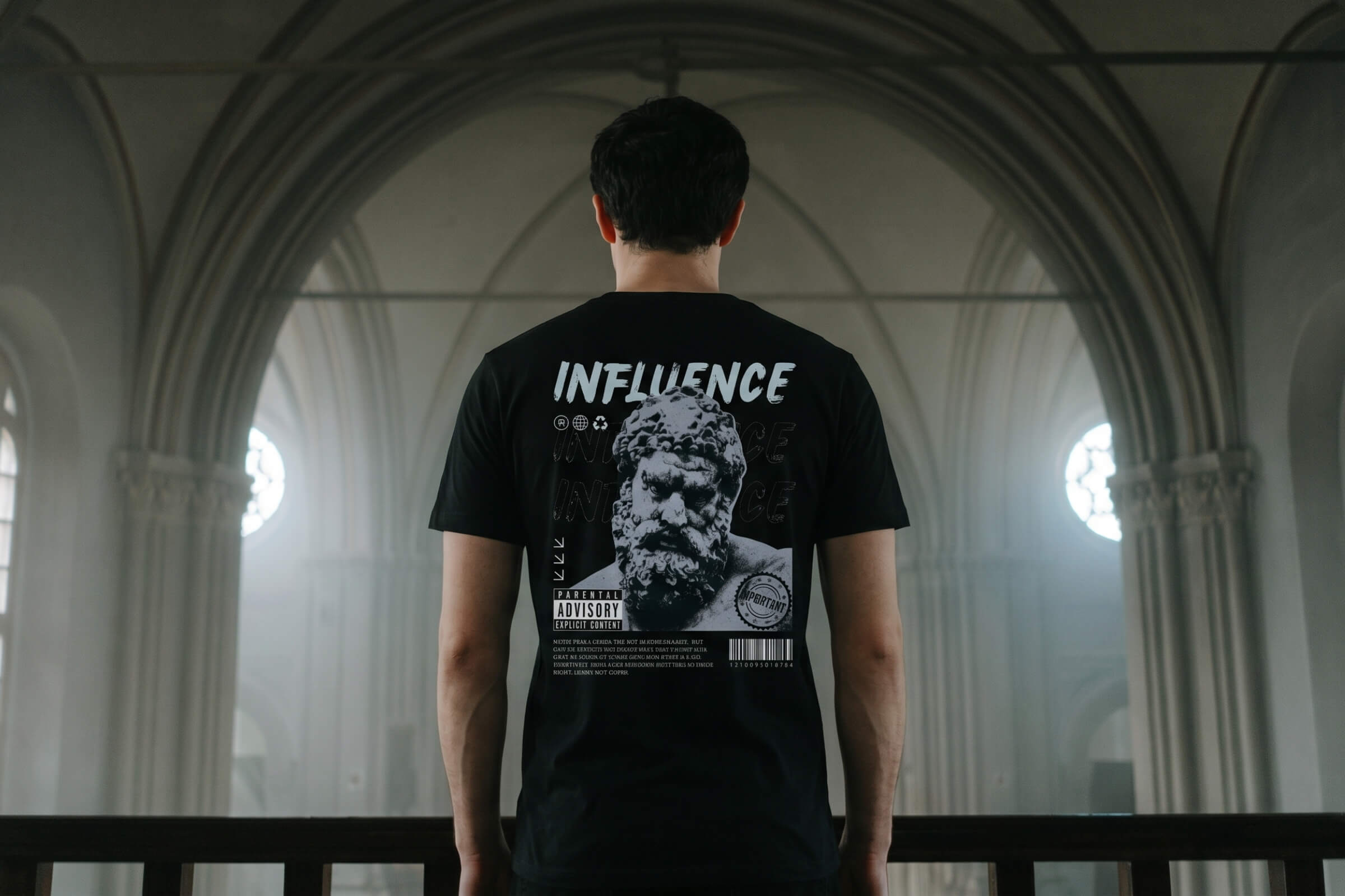 Person wearing an IKIRU graphic shirt with the word ''influence'' on the back. Standing in a big church hall